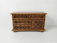 Front view of carved wood jewelry chest showing drawers and side door