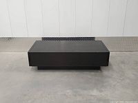 Front view of matte black pedestal coffee table, drawers closed