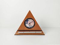 Front view showing triangular teak case, clock face with Great Wave design, and metal chime bar