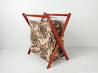 three-quarter front view showing hardwood X-frame and tapestry bag