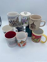 All eight mugs stacked showing variety of designs