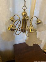 Chandelier suspended to show brass frame and five frosted tulip shades