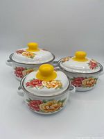 Three covered enamel saucepans front view