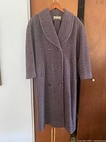 Full view of long double-breasted wool coat hanging