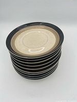 Stack of ten 6" Mikasa DuraStone plates showing black rims and tan bands