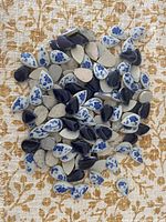 Pile of mixed solid navy and floral cream teardrop ceramic tiles
