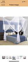 stock image of assembled white four-corner mosquito net canopy over bed