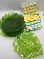 Stack of dark green plates, light green plate, two sealed napkin packs