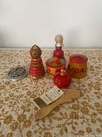 Group shot of all items: love spoon, three wooden boxes, two dolls, pewter trivet