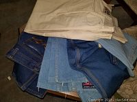 Top view of folded vintage pants showing multiple pairs of denim jeans in different shades and light-colored pants.