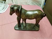 Overall view of bronze sculpture of woman hugging horse from the side showing entire figure and base.
