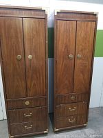 Full view from front of both tall wooden Thomasville cabinets showing doors, drawers, brass hardware, and wood finish.