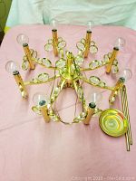 Top view showing the brass chandelier with eight arms, glass circular ornaments, and fitted light bulbs. Wiring visible.