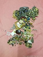 Wide view of assorted jewelry pieces displayed on a cloth background showing various chains, floral and animal motifs, beads, and pendants.