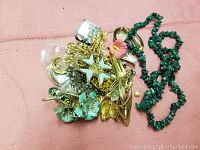 Assorted repurposed jewelry pieces on pink fabric