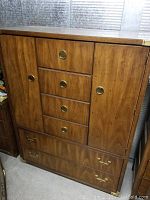 Front view of chest showing central drawers, side doors, and bottom drawer with brass hardware