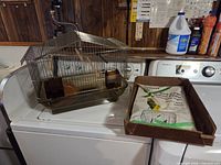 Wire bird cage and gravel paper pack on washing machine