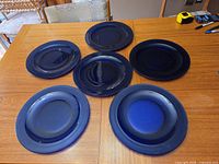 six cobalt blue glass charger plates laid out on wooden table