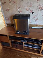 Front view of stainless steel dual compartment waste bin on cabinet