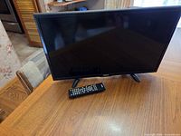 Front view of RCA flat screen television on table with remote