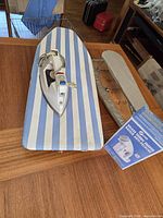 Iron, tabletop board, sleeve board and Conair shaver box grouped on table