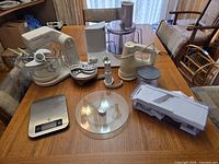 All items arranged on table: stand mixer, food processor, hand mixer, mandoline, scale