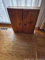 Front view of closed butternut wood cabinet