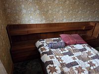 Full view of teak headboard with shelving and part of mattress, pillows excluded