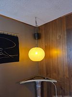 Lamp hanging in room, full view showing chain, shade and surrounding wall