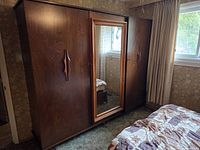 Front view showing three-door teak armoire with centre mirror and sculpted handles