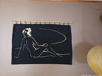 Full view of tapestry on wall showing design and bamboo rod