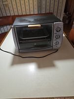 Full view of toaster oven front, door closed, power cord visible