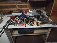 Workbench view showing assorted hand tools, clamps, drill, miter saw, tool cases