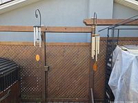 Both wind chimes hanging on fence showing size and style