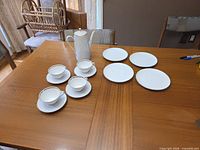 entire coffee service on table showing coffeepot, cups, saucers and plates