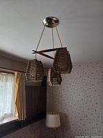 Overall view of wooden three-shade pendant light hanging from ceiling