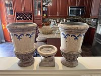 Front view of two ceramic urns and small candle holder on counter