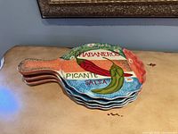 Stacked view showing all four handled plates with pepper motif and text