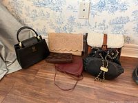Group shot of six handbags and purses on floor