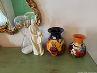All four decor items on tabletop: hourglass, figurine, two vases
