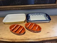 Group shot showing all dishes: yellow/white Villeroy & Boch baker, blue floral baker, two terracotta divided dishes