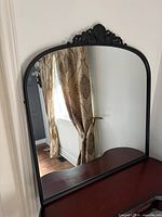 Front view of black metal arched mirror on dresser