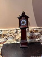 Front view of miniature grandfather clock on table