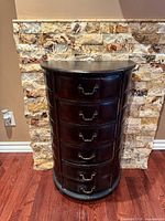 Front view of brown faux leather demilune cabinet showing six drawers and hardware