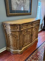 Front and right side view of carved wooden sideboard beneath framed artwork