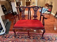 Front view of carved Chippendale style settee showing red upholstered seat and back detail