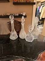 Front view of four crystal decanters with stoppers on marble surface
