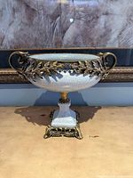 Front view of footed ceramic bowl with metal mounts and handles