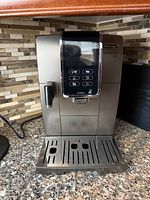 Front view of De'Longhi Dinamica Plus showing display, control panel, drip tray and frother nozzle