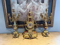 Full front view of mantel clock flanked by two matching candelabras